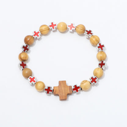 A beaded bracelet featuring natural wood beads, red cross-shaped beads with white borders, and a larger wooden cross centerpiece, displayed on a clean white background.
