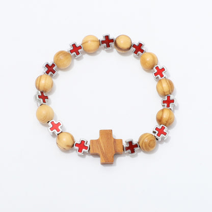 A beaded bracelet featuring light natural wood beads, red enamel cross charms with silver borders, and a central wooden cross, displayed on a clean white background.
