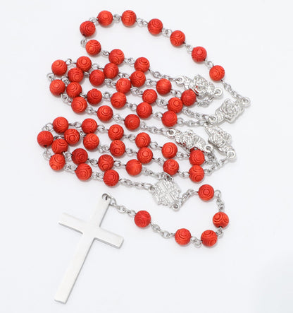 A rosary necklace featuring textured red beads and silver-tone metal links, chain, centerpiece, and a matching cross pendant, displayed on a clean white background.