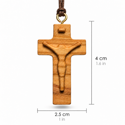 A wooden crucifix pendant with a carved figure of Jesus on a light brown wood grain background, hanging from a dark brown cord with a gold-colored metal loop. Black dimension lines and text indicate a height of 4 cm (1.