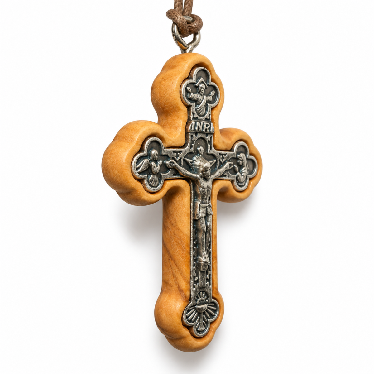 A wooden and metal crucifix pendant necklace on a white background. The cross features a light brown olive wood frame with a silver-toned metal center depicting Jesus Christ on the cross, with an INRI plaque at the top and a brown cord loop at the very top. At an Angle