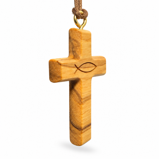 A wooden Christian cross pendant with a natural olive wood grain pattern and an engraved fish symbol, hanging from a brown cord with a gold metal ring, shown against a plain white background.