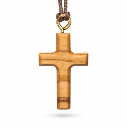 A wooden cross pendant with a natural light brown wood grain finish, hanging from a brown braided cord with a gold-colored metal loop at the top, shown against a plain white background.