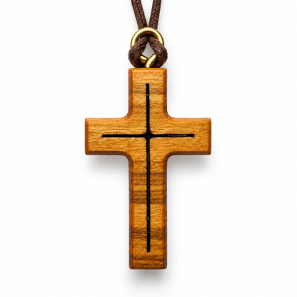 A wooden cross pendant with a black engraved cross design, hanging from a brown cord with a gold metal ring, shown on a plain white background.