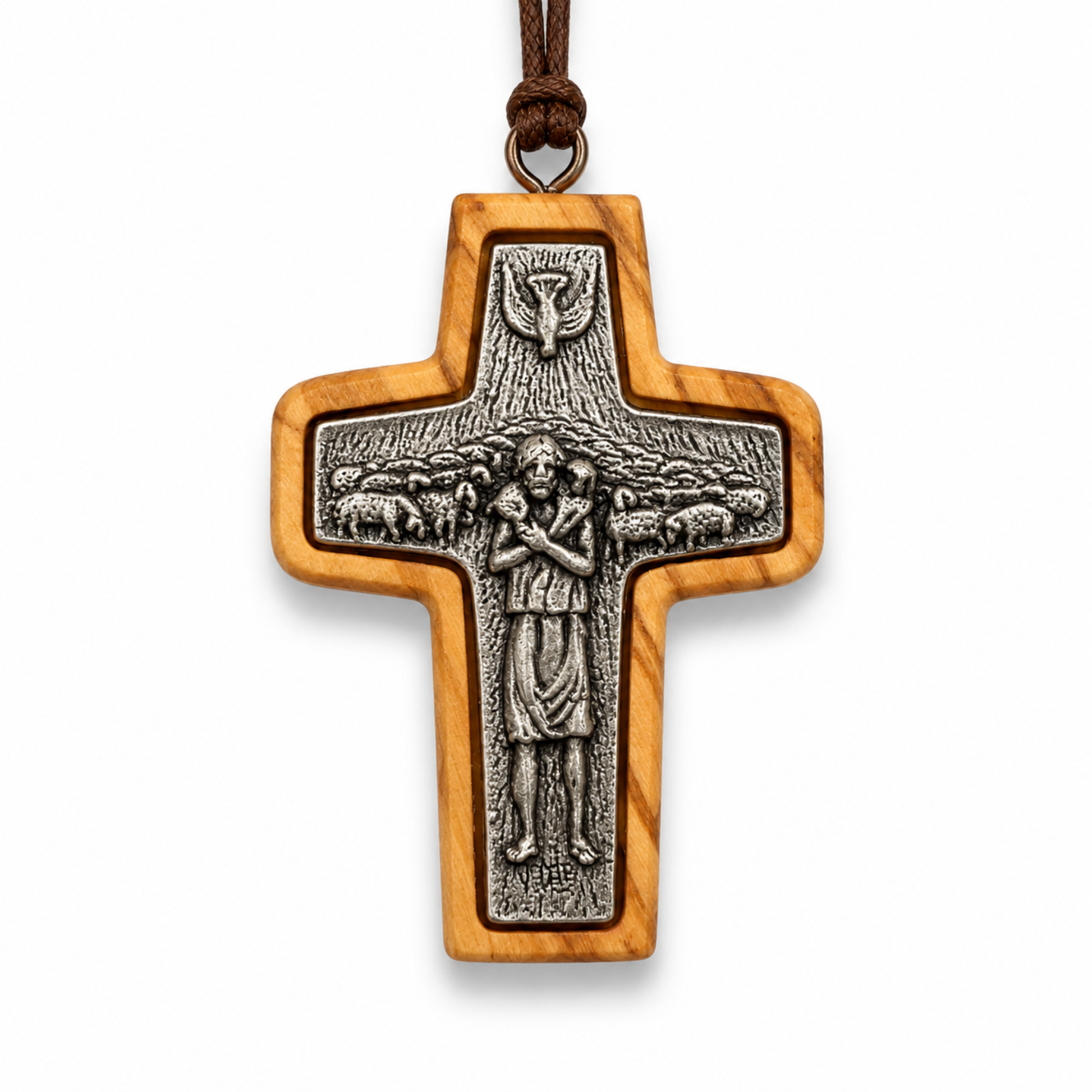 A wooden cross pendant with an olive wood grain finish and a detailed silver-toned metal centerpiece depicting Jesus and sheep, suspended by a brown cord on a white background.