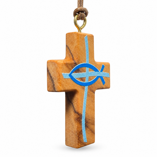 A wooden Christian cross pendant with a natural warm brown wood grain, featuring a blue Ichthys fish symbol and a vertical light blue cross. The cross hangs from a brown cord with a gold-colored metal ring, shown against a plain white background.