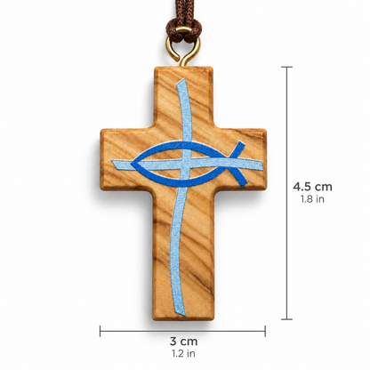 A wooden cross pendant with a blue and silver embroidered Ichthys symbol, hanging from a brown cord with a gold-colored metal ring, shown against a plain white background. Including size.