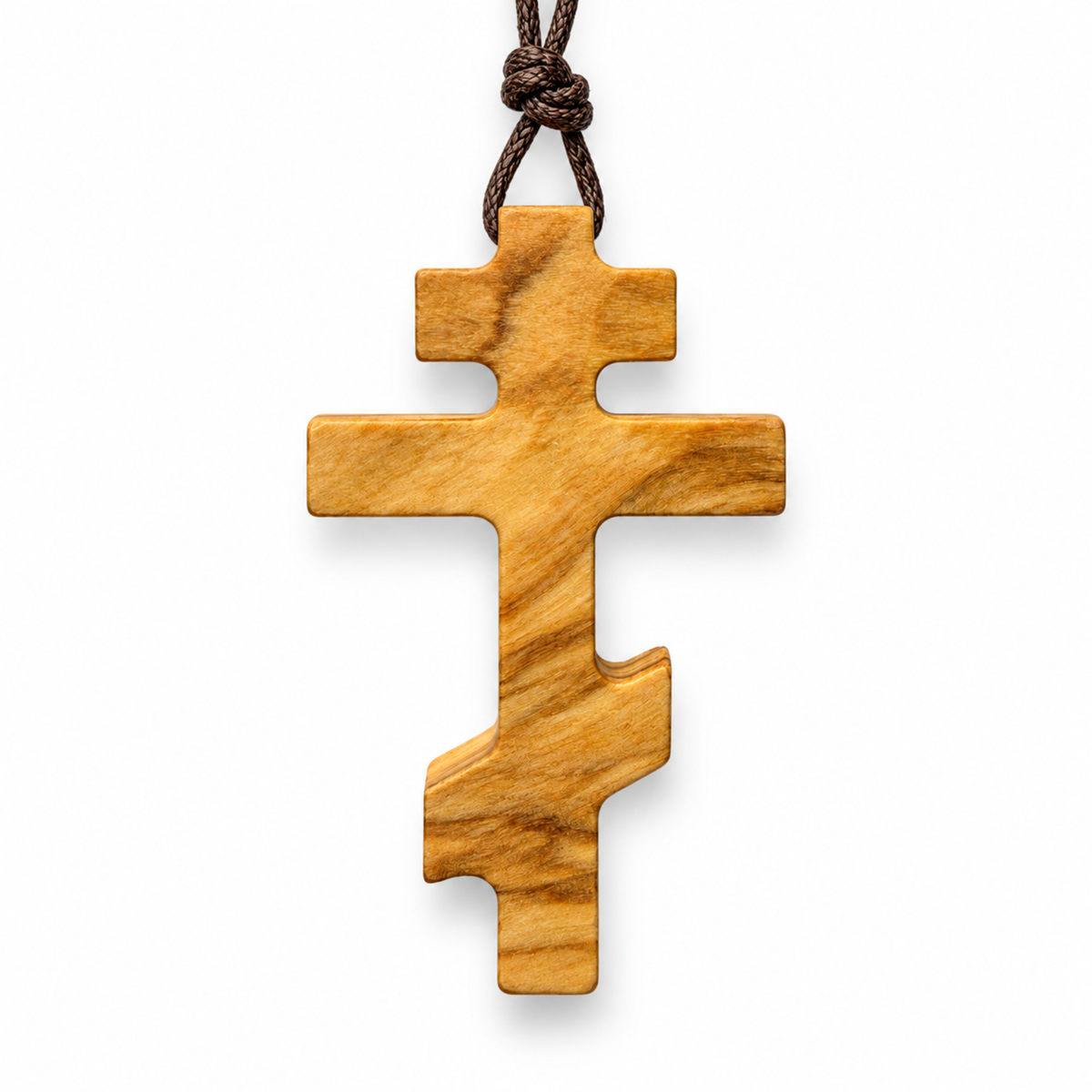 An olive wood Orthodox cross pendant with a natural grain pattern, hanging from a dark brown knotted cord on a white background.