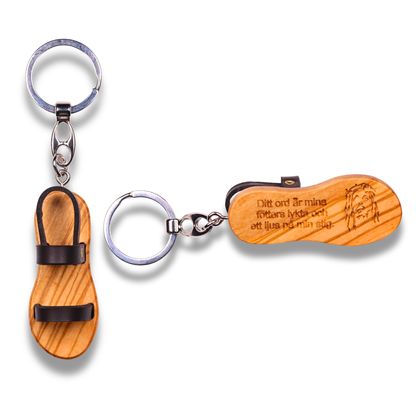 Wooden sandal-shaped keychains with engraved text on a white background