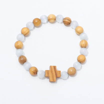 A beaded stretch bracelet featuring alternating light brown wooden beads, translucent white beads, and a central wooden cross charm, displayed on a clean white background.
