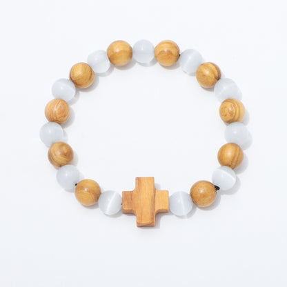 A beaded stretch bracelet featuring alternating light brown wooden beads and translucent white cat's eye beads, finished with a central wooden cross charm, shown on a plain white background.