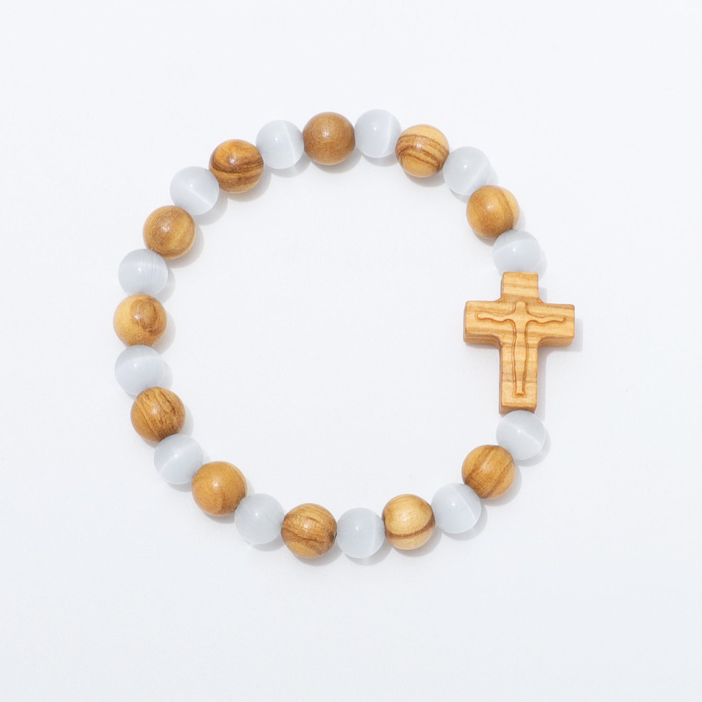 A beaded stretch bracelet featuring light brown wooden beads, translucent white cat's eye beads, and a carved wooden crucifix, displayed on a clean white background.