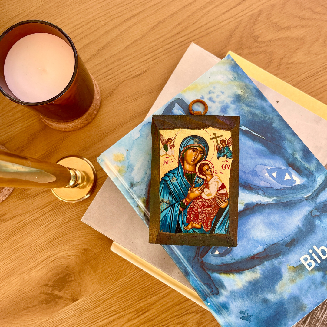 Icon of a religious figure on a book with a candle on a wooden surface