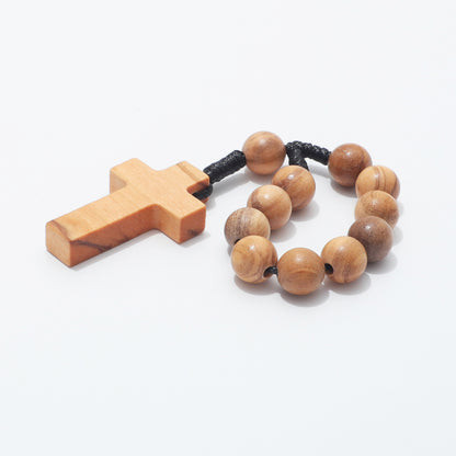 Low angled view of the plain wooden cross beside a loop of 10mm olive wood beads