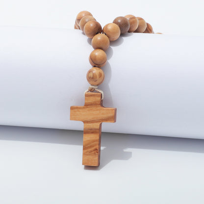 Plain olive wood cross hanging below three drop beads on natural cord