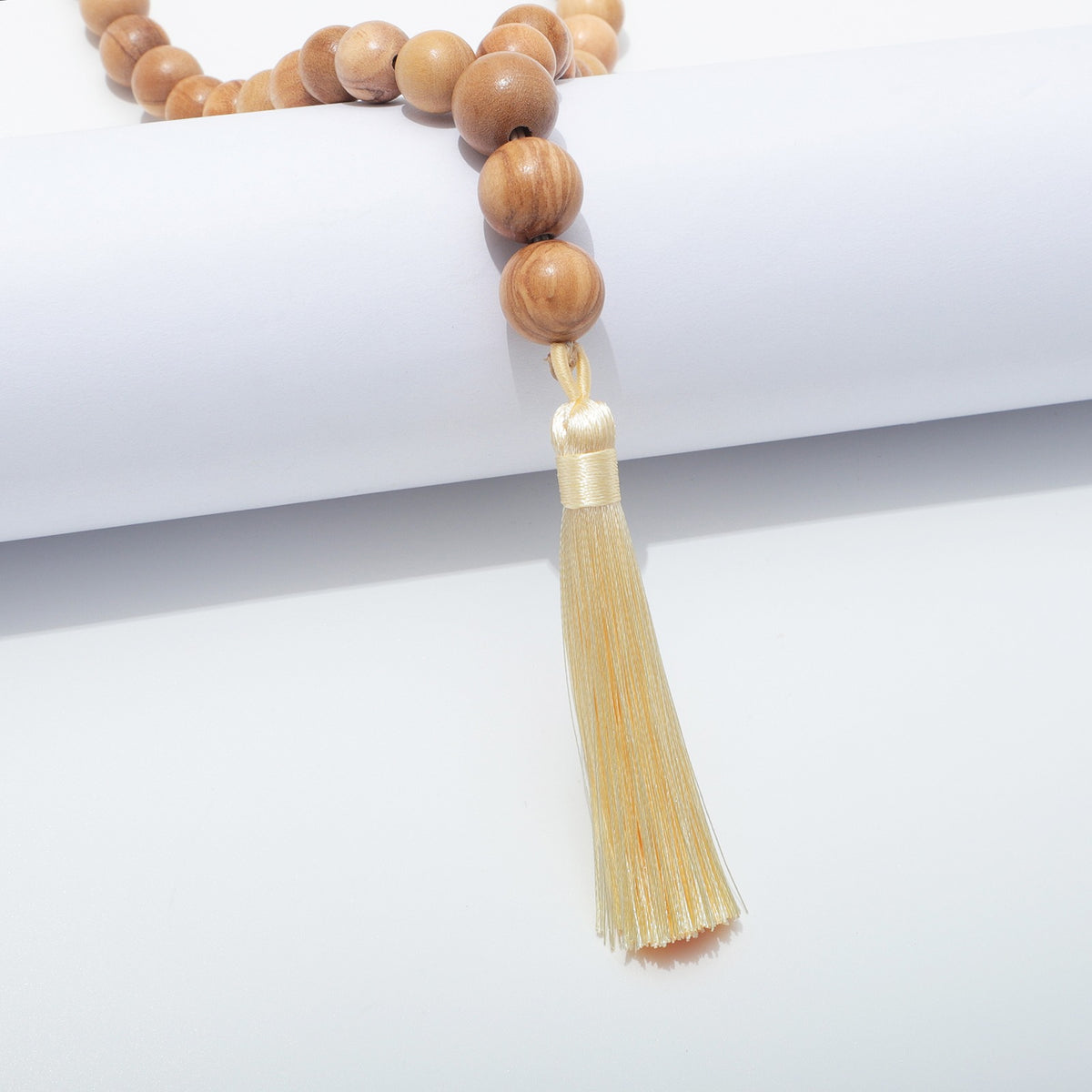 Cream tassel beneath three larger olive wood beads