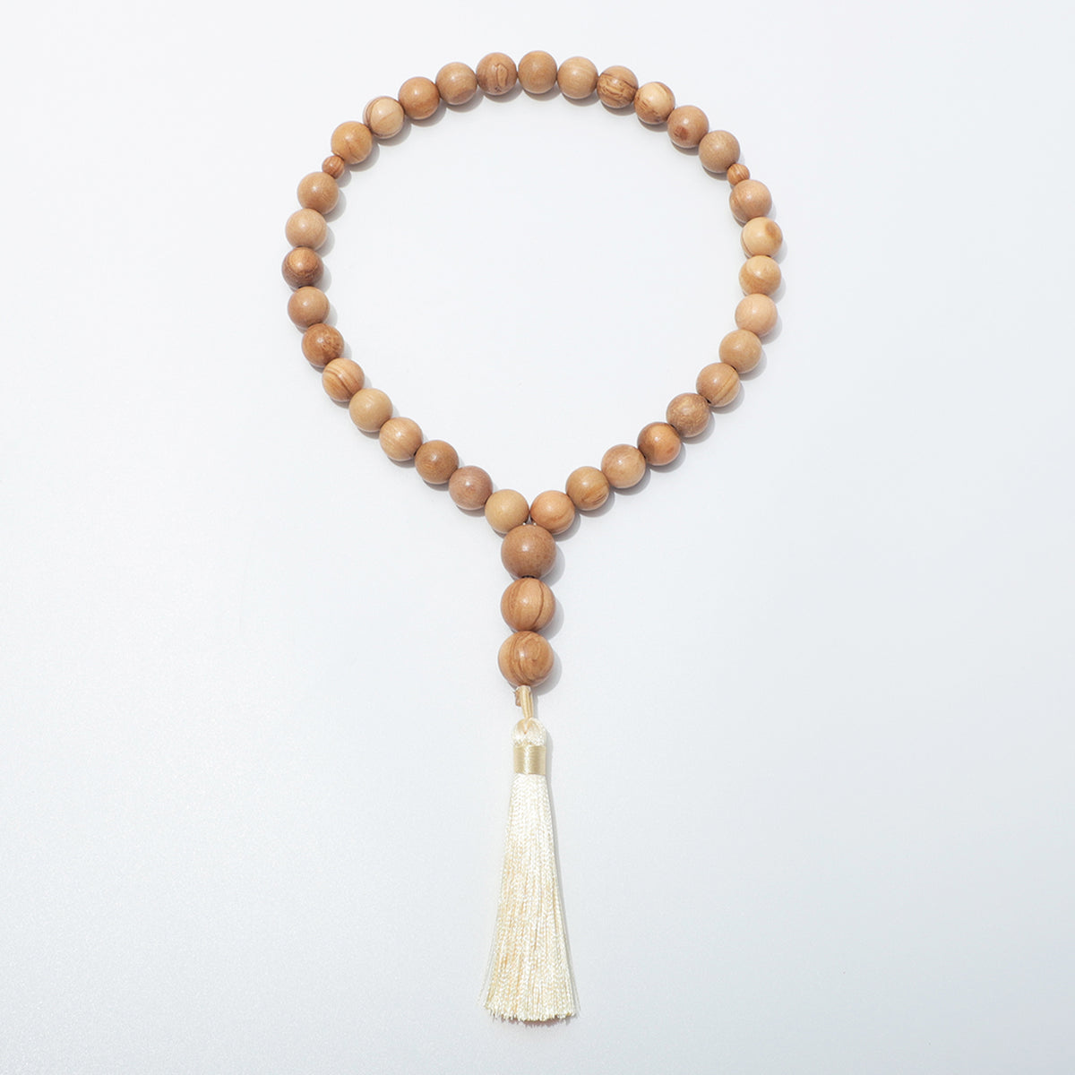 Full front view of olive wood prayer beads with two small dividers and three beads above a cream tassel