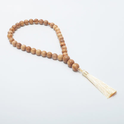 Side view of olive wood prayer beads showing the loop and cream tassel
