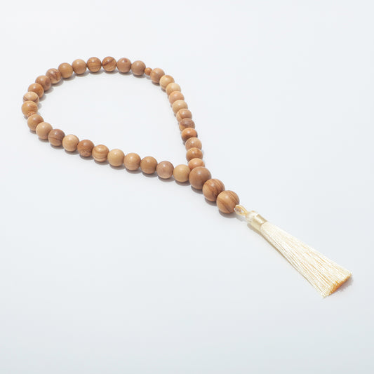 Side view of olive wood prayer beads showing the loop and cream tassel