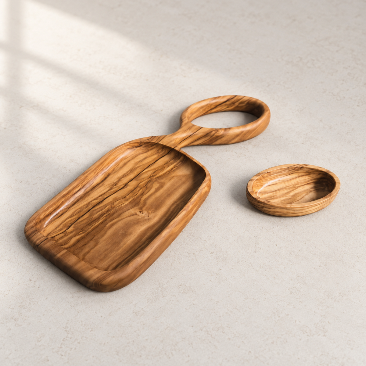 Olive wood serving tray and removable oval plate on a light stone tabletop in natural daylight