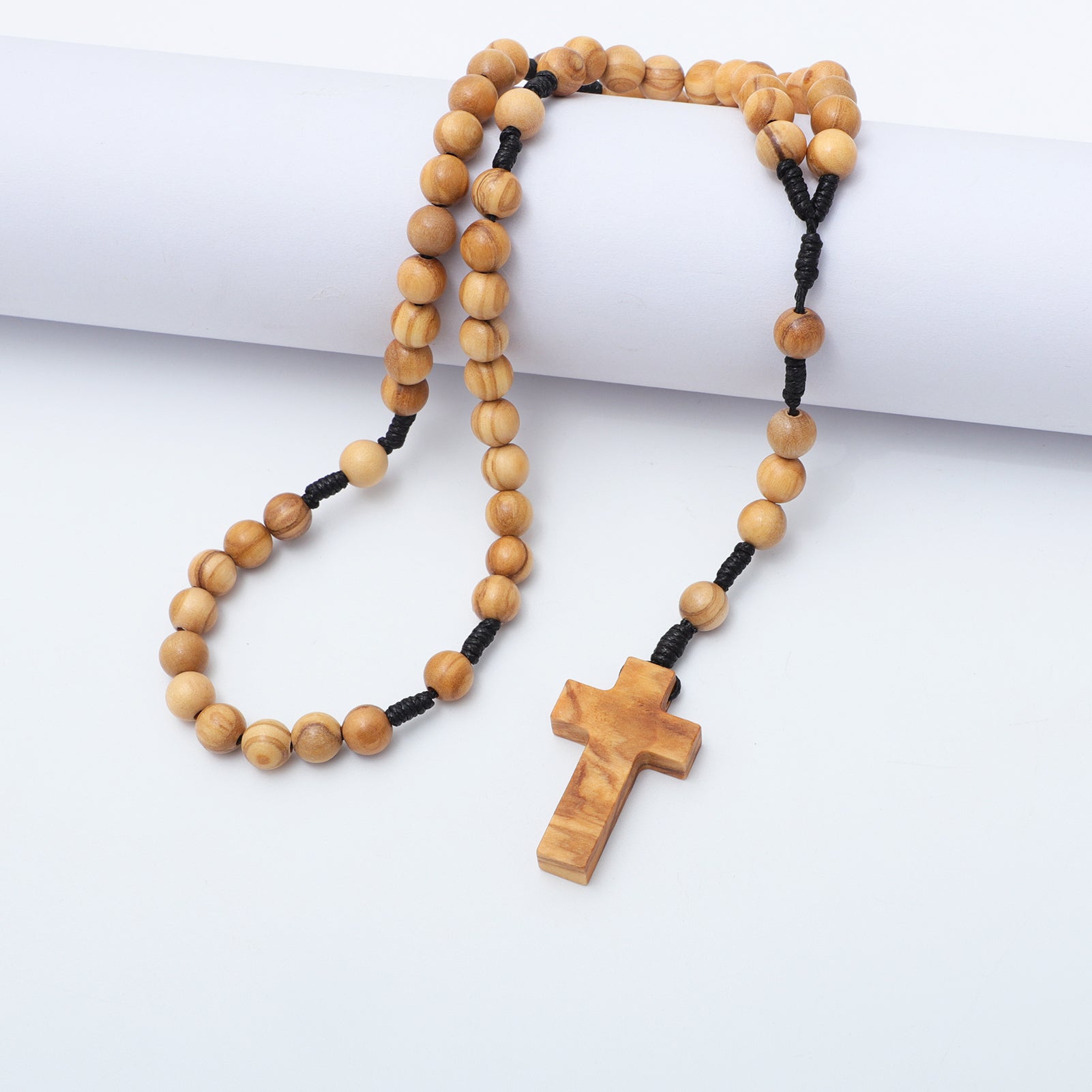 Wooden rosary with a cross on a white surface